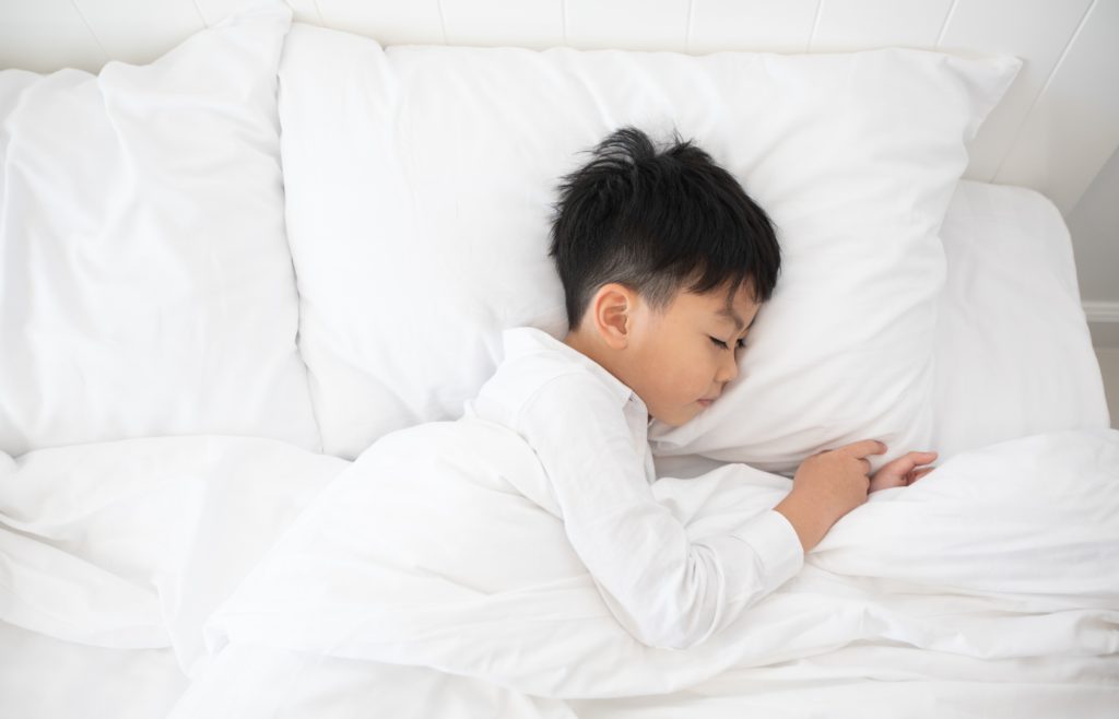 A boy sleeps comfortably in bed because the thermostat is set to the optimal heat temperature for their home. 