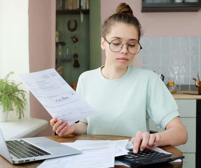 Woman noticing her energy bills rising which can be a sign that her cooling system is losing efficiency.
