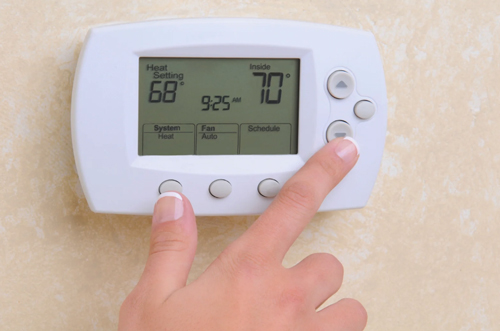 Traditional programmable thermostat being adjusted for heating and cooling schedules after Pierce Refrigeration installation service