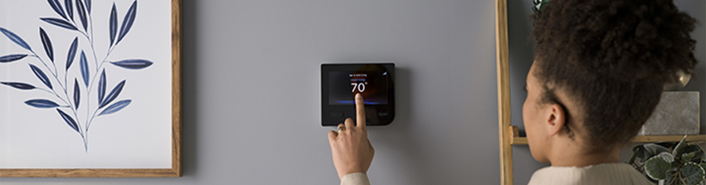 Homeowner adjusting smart thermostat for optimal comfort and energy efficiency with Pierce Refrigeration professional installation